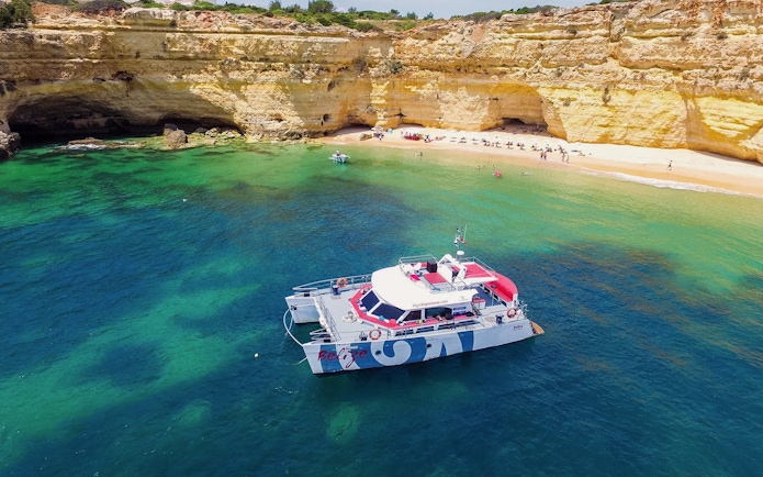 Catamaran near Benagil Cave with beach and cliffs, Albufeira cruise.