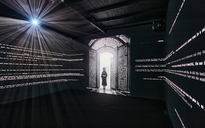 Interactive light installation at Light Art Museum with illuminated text and silhouette figure.