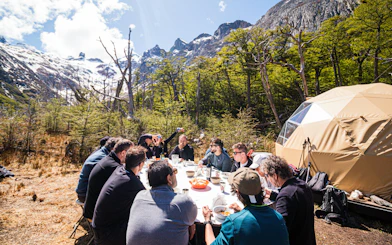 Group enjoying snacks break during Esmeralda Lake Trekking with mountains in the background.