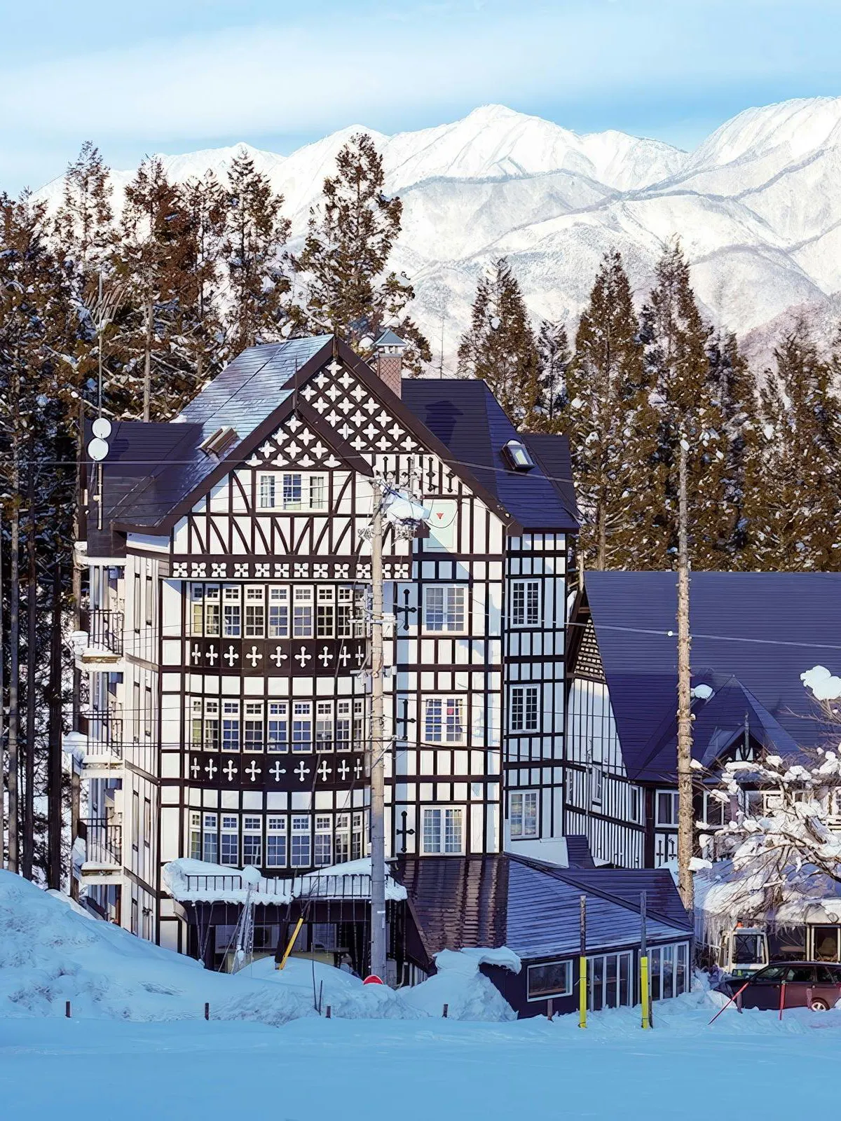 Tudor-style lodge at Hakuba47 Mountain Resort with snow-covered trees and mountains.