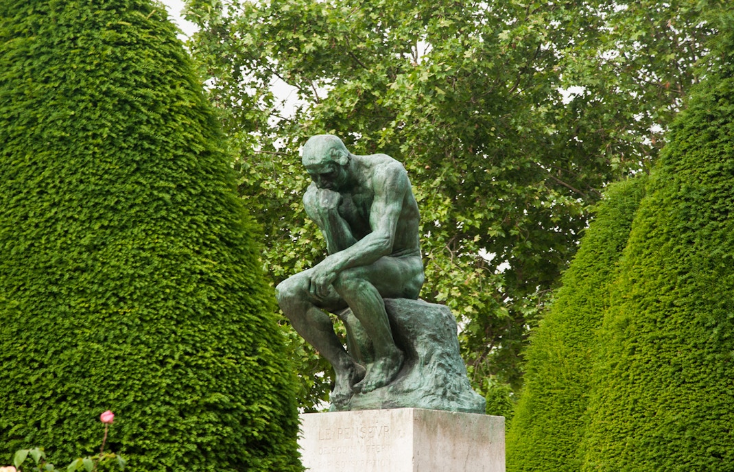 Rodin's The Thinker sculpture in a serene garden setting, Paris, France.