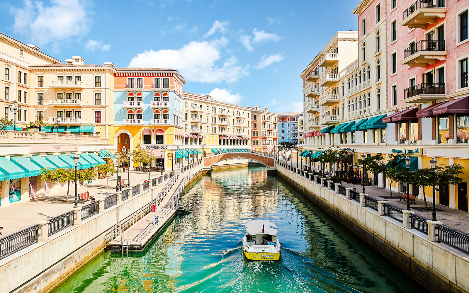 Canal with colorful buildings and a boat in Venice replica, The Pearl Island, Qatar.