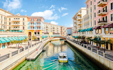 Canal with colorful buildings and a boat in Venice replica, The Pearl Island, Qatar.