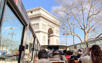 Tourists on a bus viewing the Arc de Triomphe during a Paris city tour.