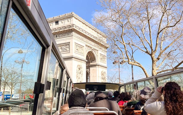 Tourists on a bus viewing the Arc de Triomphe during a Paris city tour.
