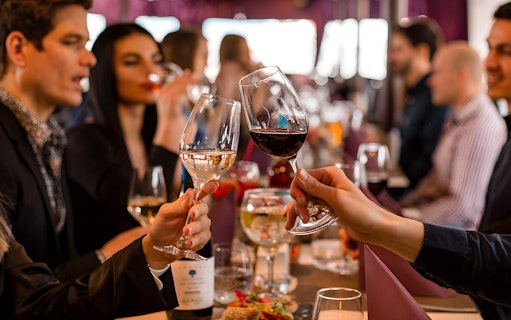 Couple toasting wine glasses on Valentine's dinner cruise, Budapest.