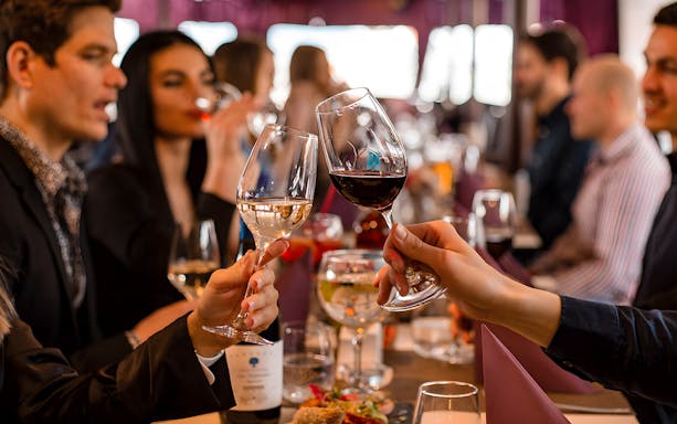 Couple toasting wine glasses on Valentine's dinner cruise, Budapest.