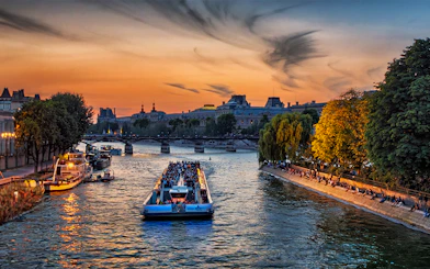 Seine River cruise boat with tourists at sunset near Eiffel Tower, Paris.