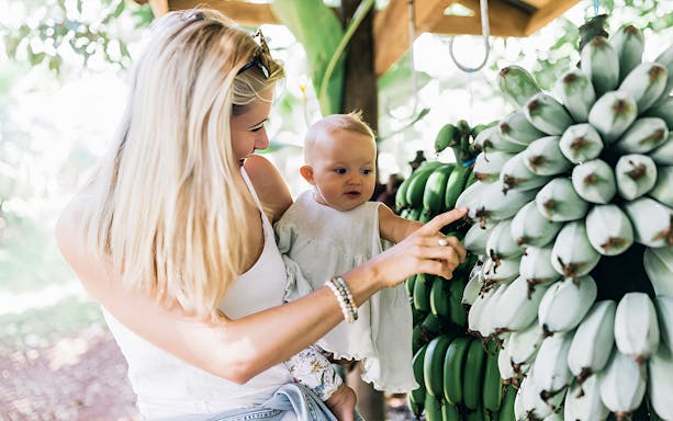 Mother and child exploring bananas at Tropical Fruit World farm tour.