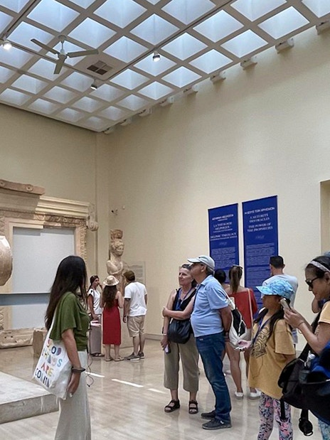 Guide explaining the Sphinx of Naxos to visitors inside Delphi Museum.