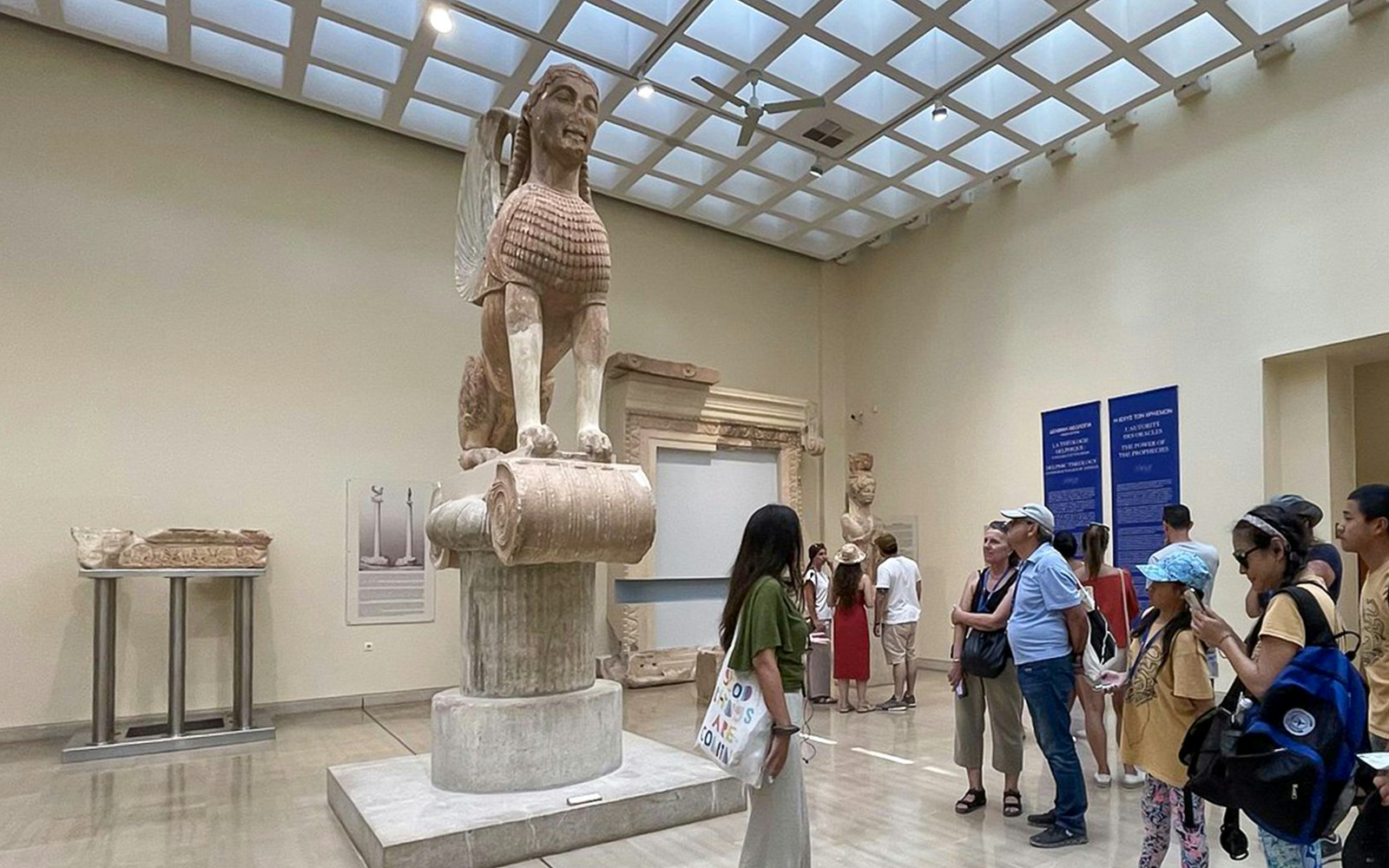 Guide explaining the Sphinx of Naxos to visitors inside Delphi Museum.