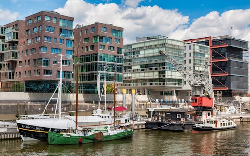 Boats docked in HafenCity with modern buildings and crane, Hamburg.