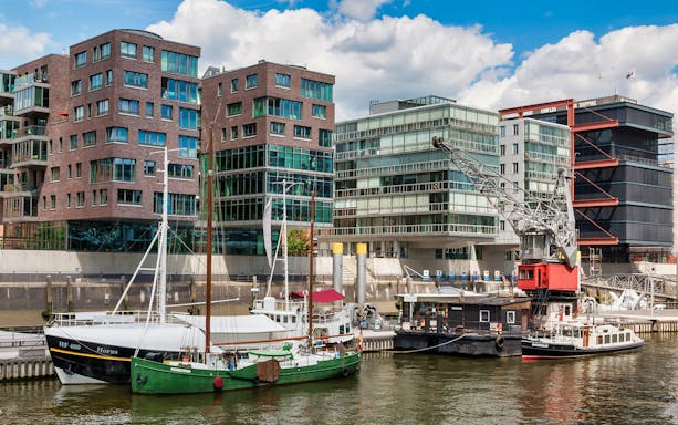 Boats docked in HafenCity with modern buildings and crane, Hamburg.