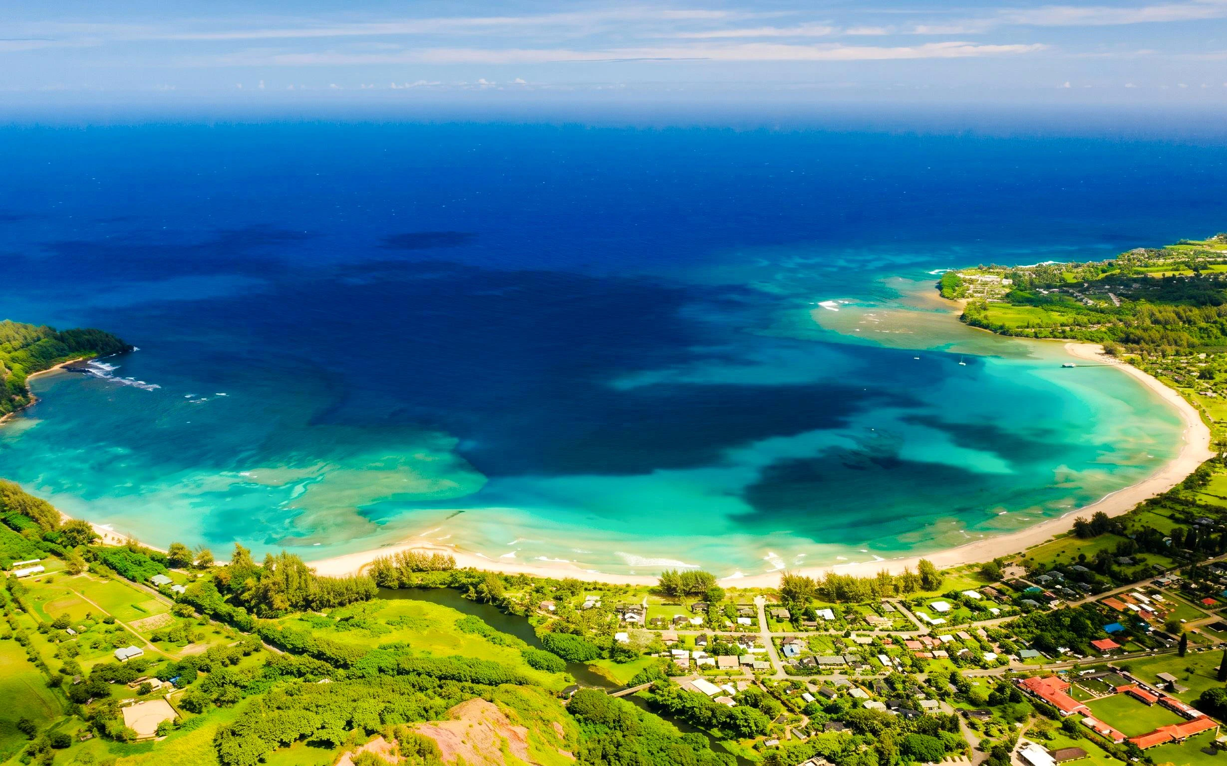 Aerial view of Kauai coastline with turquoise waters and lush greenery.