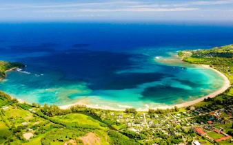 Aerial view of Kauai coastline with turquoise waters and lush greenery.
