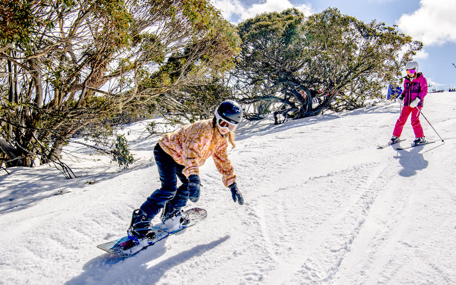 Snowboarder and skier on a snowy slope at Mt Buller, Australia.