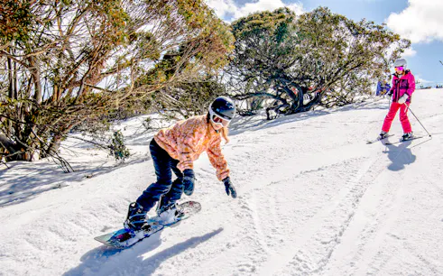 Snowboarder and skier on a snowy slope at Mt Buller, Australia.
