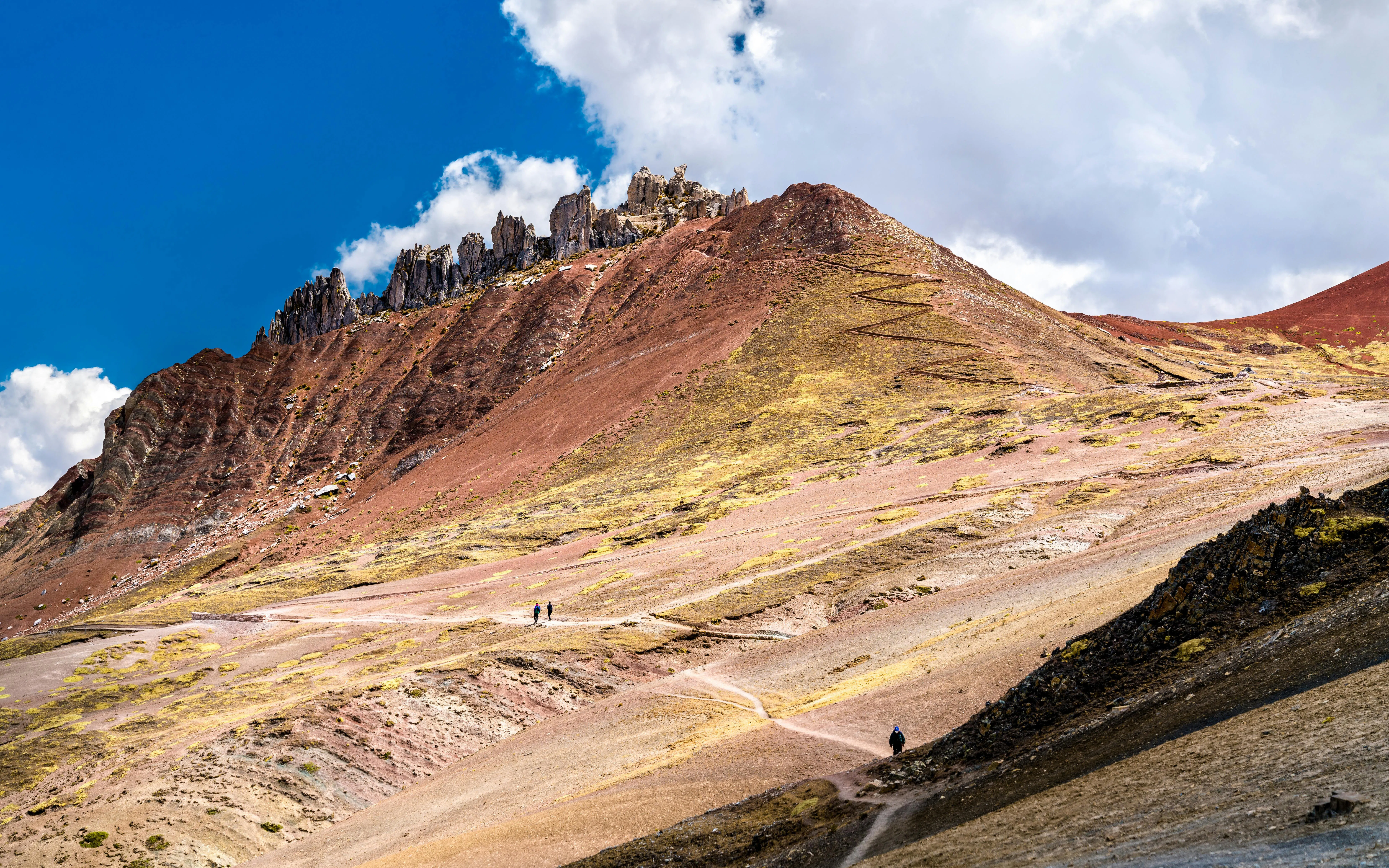 Stone formations at Palccoyo Rainbow Mountains near Cusco, Peru, with hikers on the trail.