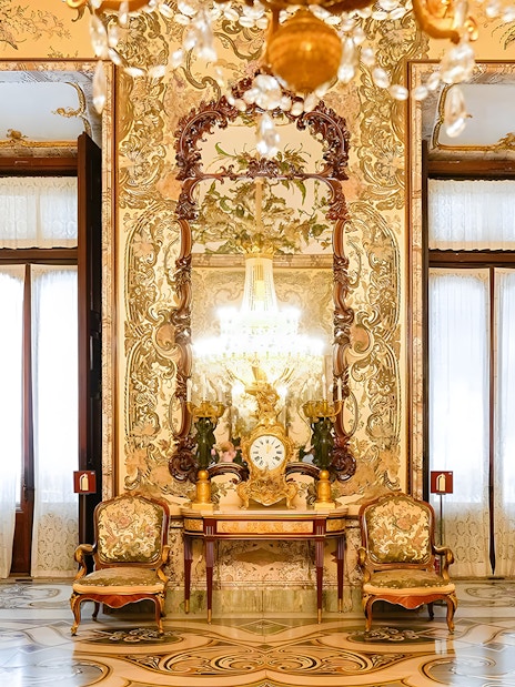 Interior of Royal Palace of Madrid with ornate decor, chandeliers, and antique furniture.