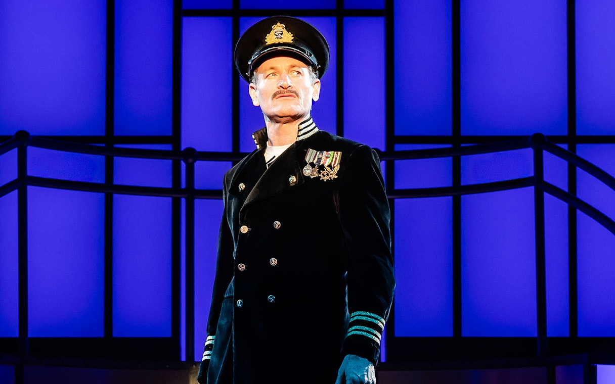 Performer in naval uniform on stage during Titanique West End show.