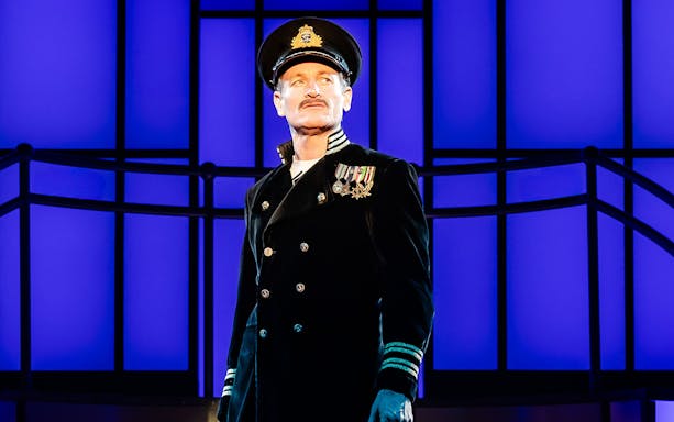 Performer in naval uniform on stage during Titanique West End show.
