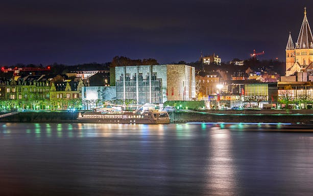 Cruise ship on the Rhine River at night with Mainz cityscape in the background.