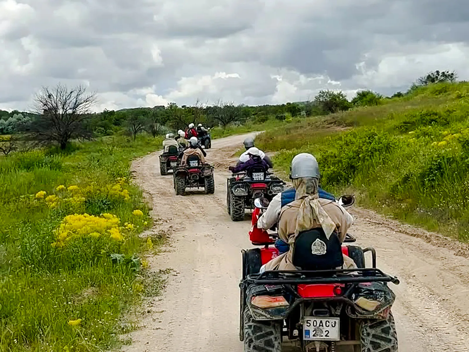 ATVs driving on a dirt path through green fields in Cappadocia.