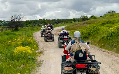 ATVs driving on a dirt path through green fields in Cappadocia.