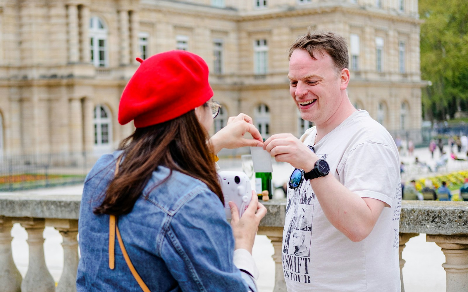 People examining a polaroid during Emily in Paris Food Tour near a historic building.