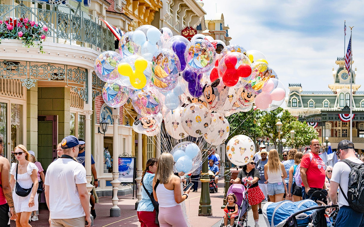 Visitors at Walt Disney World Orlando with colorful character balloons.