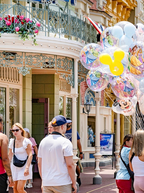 Visitors at Walt Disney World Orlando with colorful character balloons.