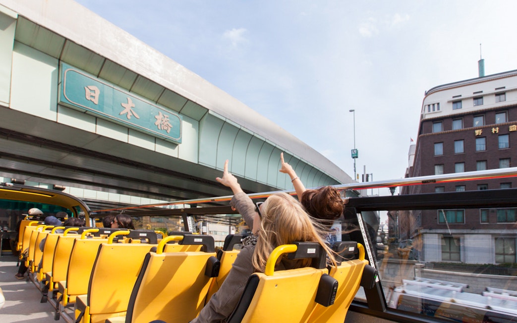 Tourists on Sky Hop bus pointing at Nihonbashi bridge in Tokyo.