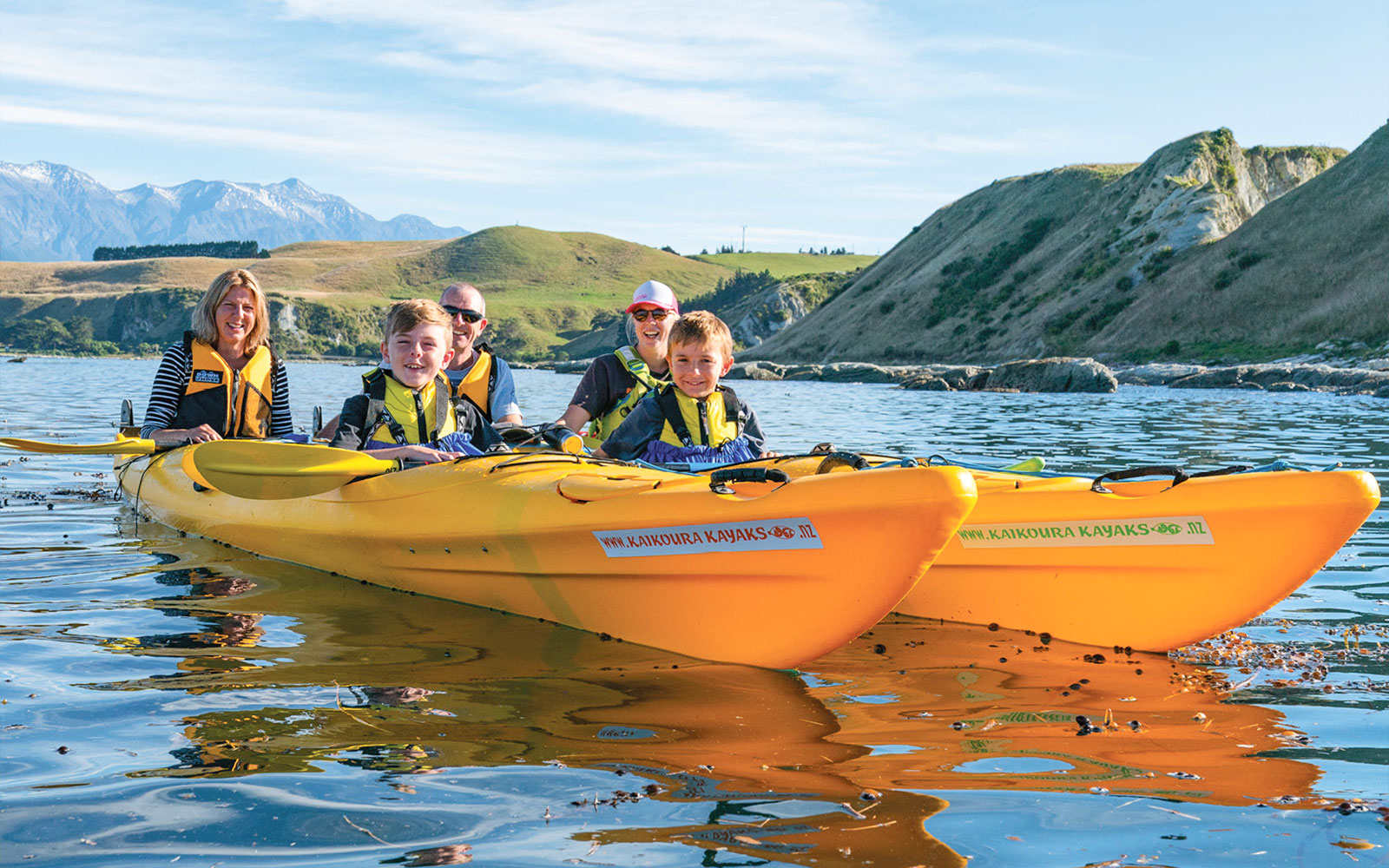 Group kayaking on scenic waters with hills in the background during a guided wildlife tour.