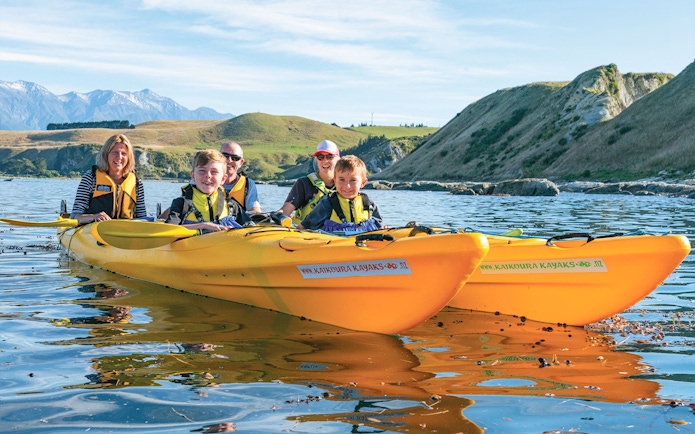 Group kayaking on scenic waters with hills in the background during a guided wildlife tour.