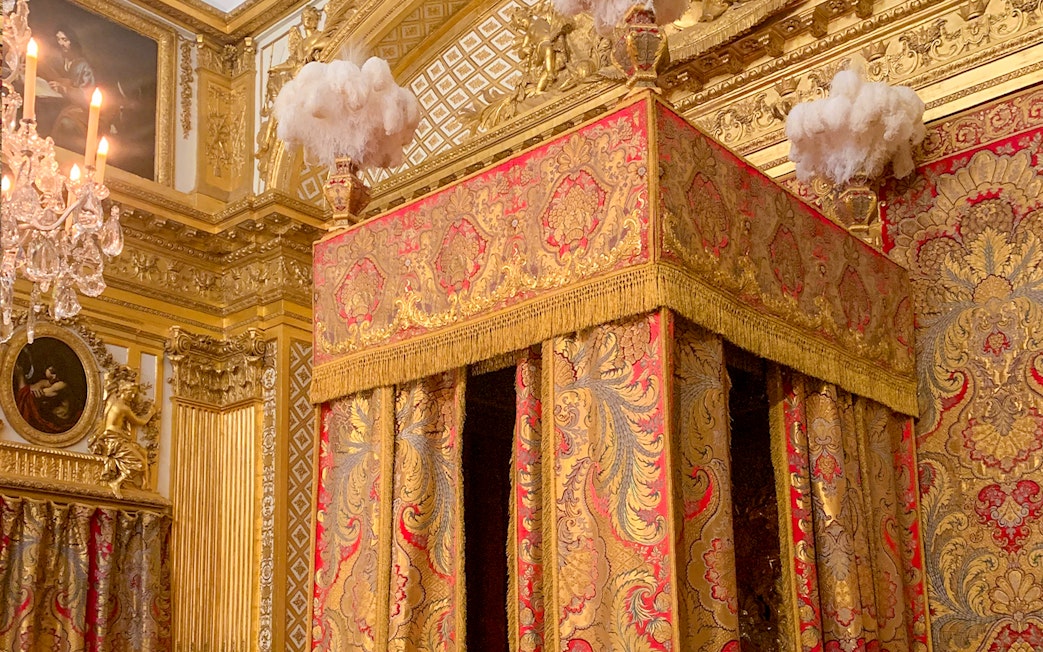 Versailles King's Apartment bedroom with ornate gold and red canopy bed.