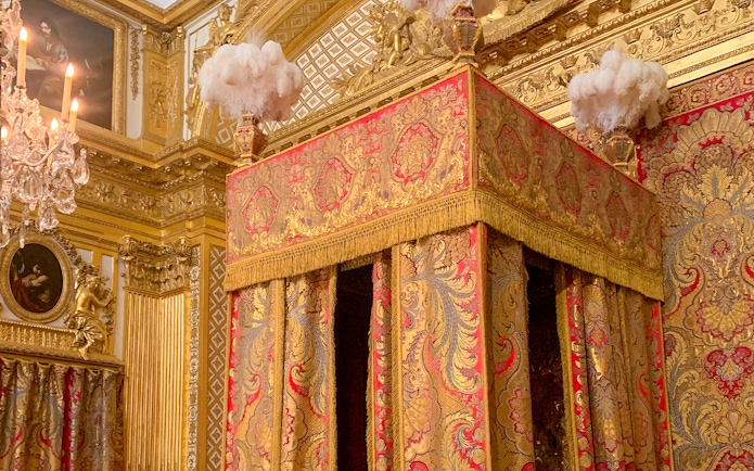 Versailles King's Apartment bedroom with ornate gold and red canopy bed.