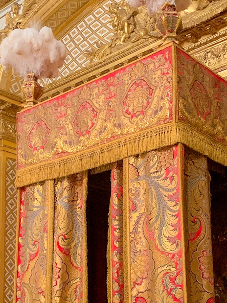Versailles King's Apartment bedroom with ornate gold and red canopy bed.