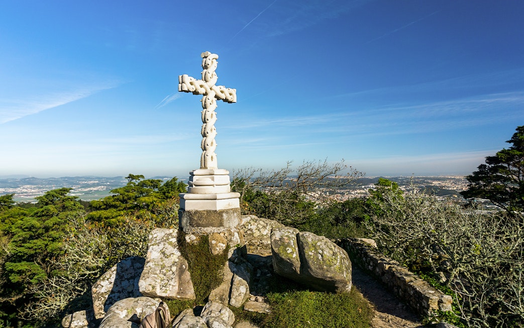 Stone cross at Cruz Alta viewpoint near Pena Palace, overlooking Sintra landscape.
