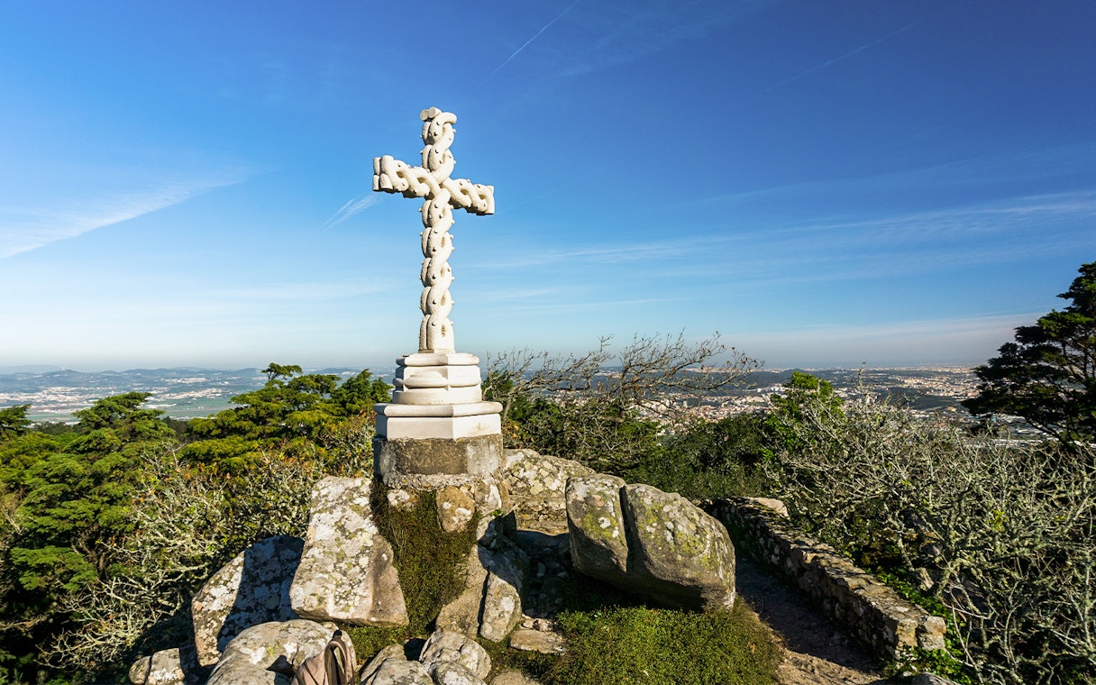 Stone cross at Cruz Alta viewpoint near Pena Palace, overlooking Sintra landscape.
