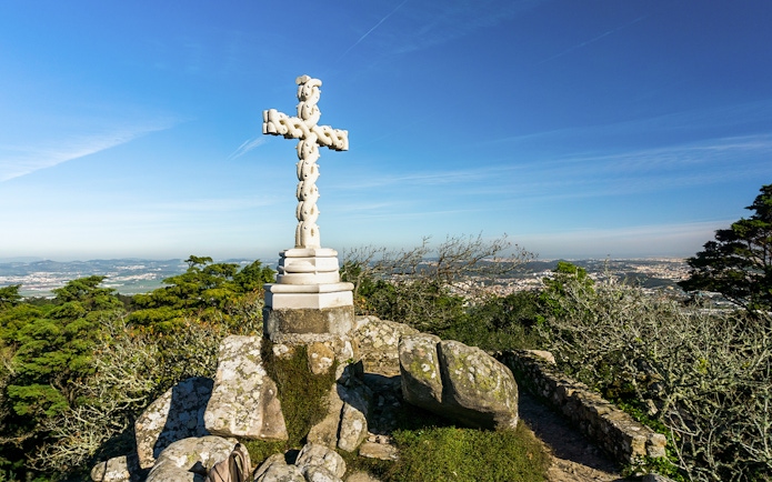 Stone cross at Cruz Alta viewpoint near Pena Palace, overlooking Sintra landscape.