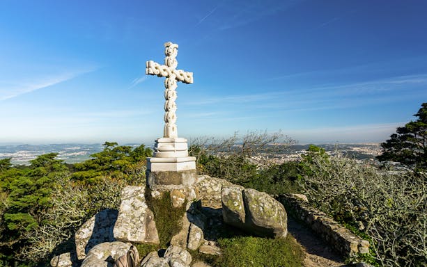 Stone cross at Cruz Alta viewpoint near Pena Palace, overlooking Sintra landscape.