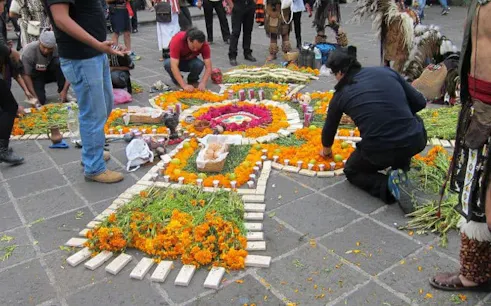 Mixquic Day of the Dead altar with marigolds and candles, people arranging offerings.