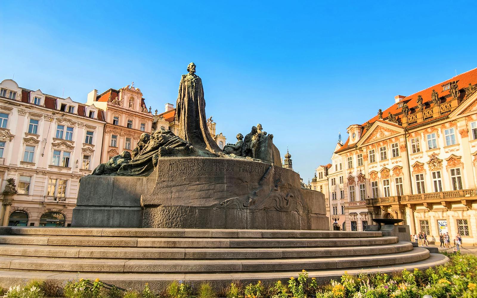 Jan Hus Memorial in Old Town Square, Prague, with historic buildings in the background.
