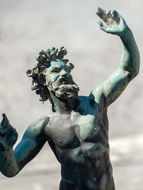 Dancing Faun statue in Pompeii, Italy, depicting a mythological figure in motion.