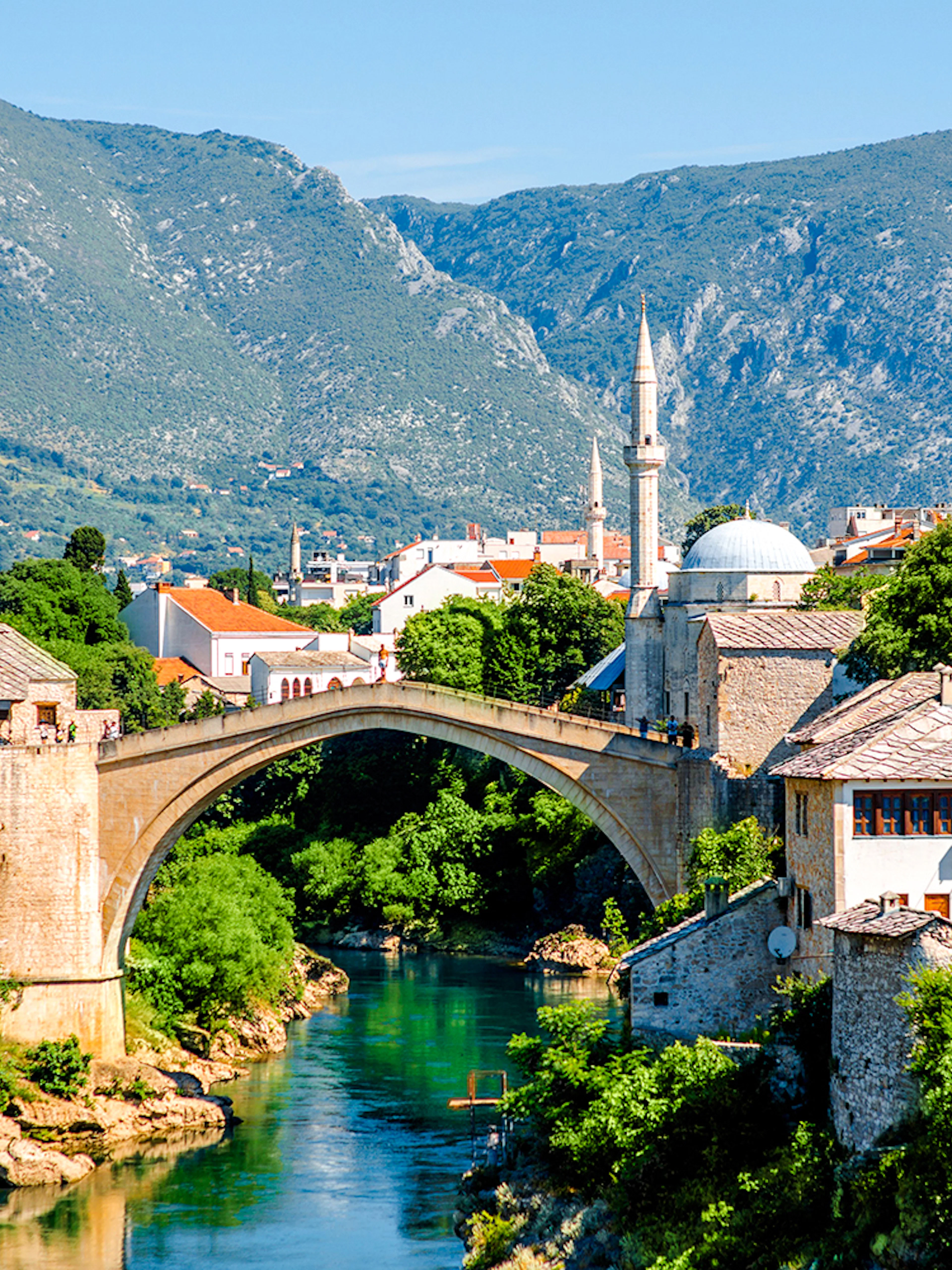 Mostar Bridge spanning the Neretva River with surrounding historic buildings in Mostar, Bosnia and Herzegovina.