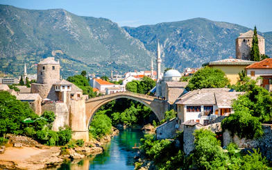Mostar Bridge spanning the Neretva River with surrounding historic buildings in Mostar, Bosnia and Herzegovina.