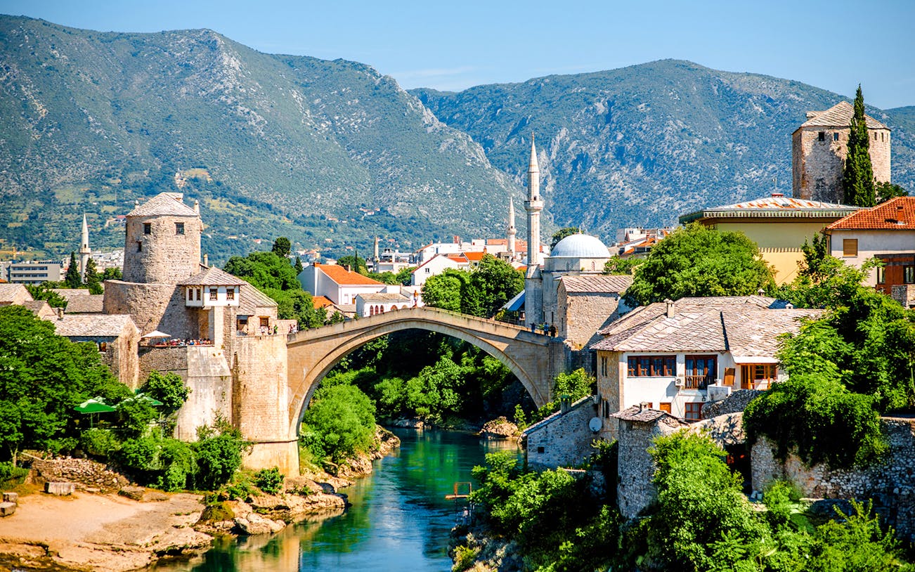Mostar Bridge spanning the Neretva River with surrounding historic buildings in Mostar, Bosnia and Herzegovina.