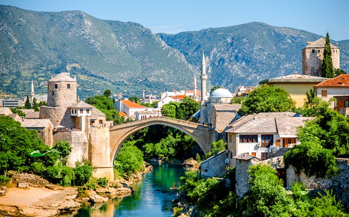 Mostar Bridge spanning the Neretva River with surrounding historic buildings in Mostar, Bosnia and Herzegovina.