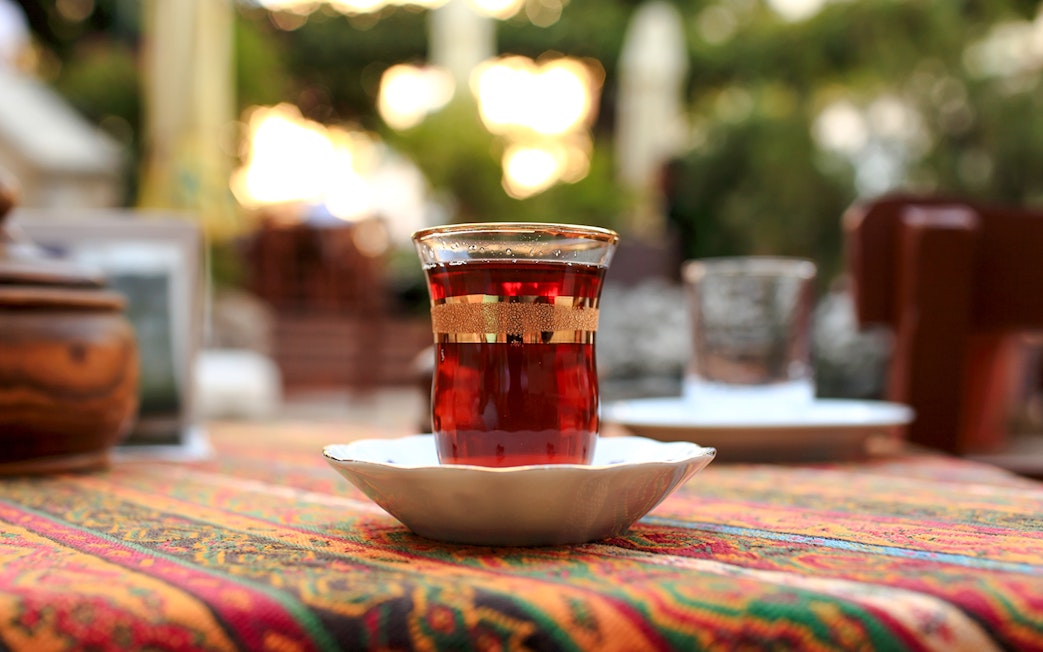 Glass of tea on a colorful tablecloth in an outdoor setting.