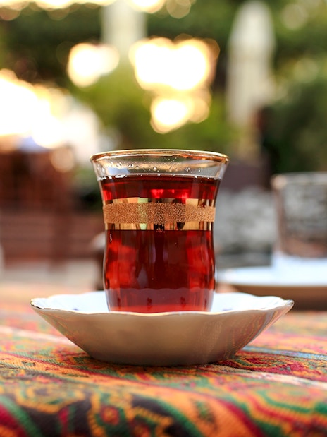 Glass of tea on a colorful tablecloth in an outdoor setting.
